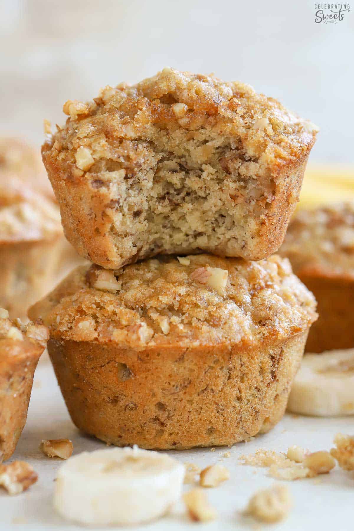A banana nut muffin with a bite taken out of it stacked on top of another muffin.