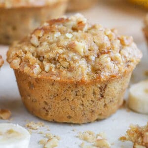 Closeup of a banana nut muffin topped with brown sugar and nuts.