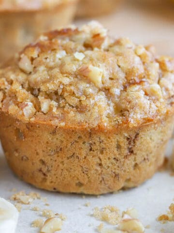 Closeup of a banana nut muffin topped with brown sugar and nuts.