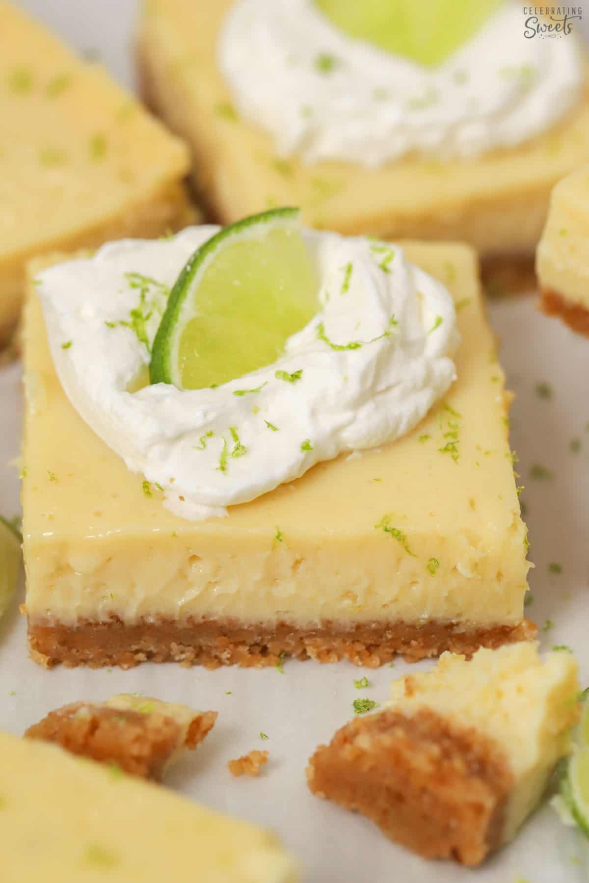 Key lime pie bar topped with whipped cream and sliced lime.