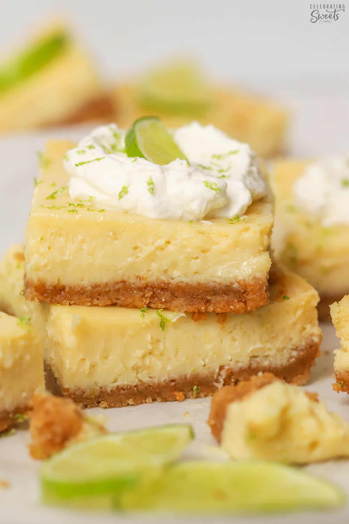 Stack of two key lime pie bars garnished with whipped cream and sliced lime.