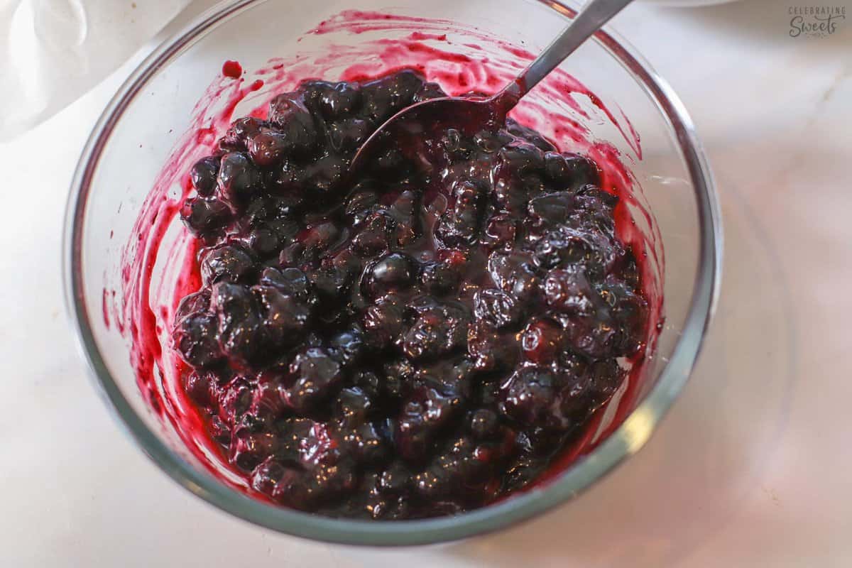 Blueberry sauce in a glass bowl with a spoon.