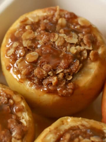 Baked apples topped with caramel in a baking dish.