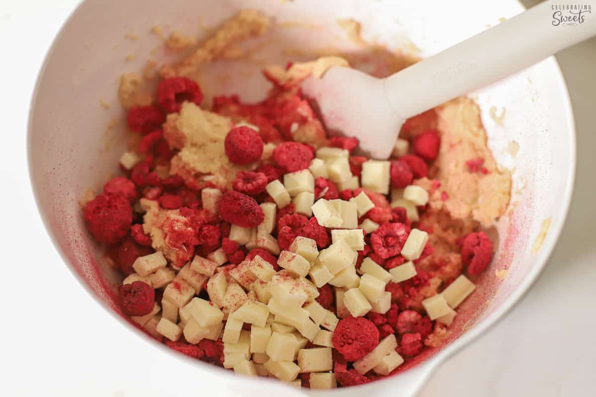 White chocolate and raspberries in a bowl of cookie dough.