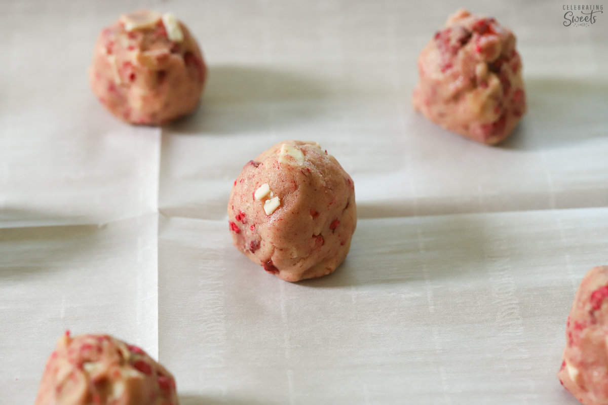 White chocolate raspberry cookie dough balls on a piece of parchment paper.