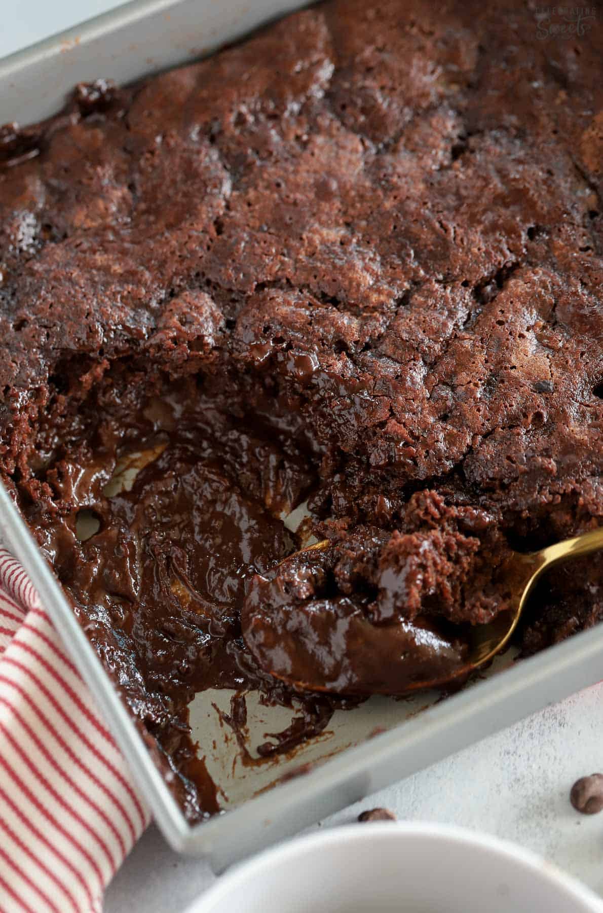 Chocolate pudding cake in a metal pan next to a red and white napkin.