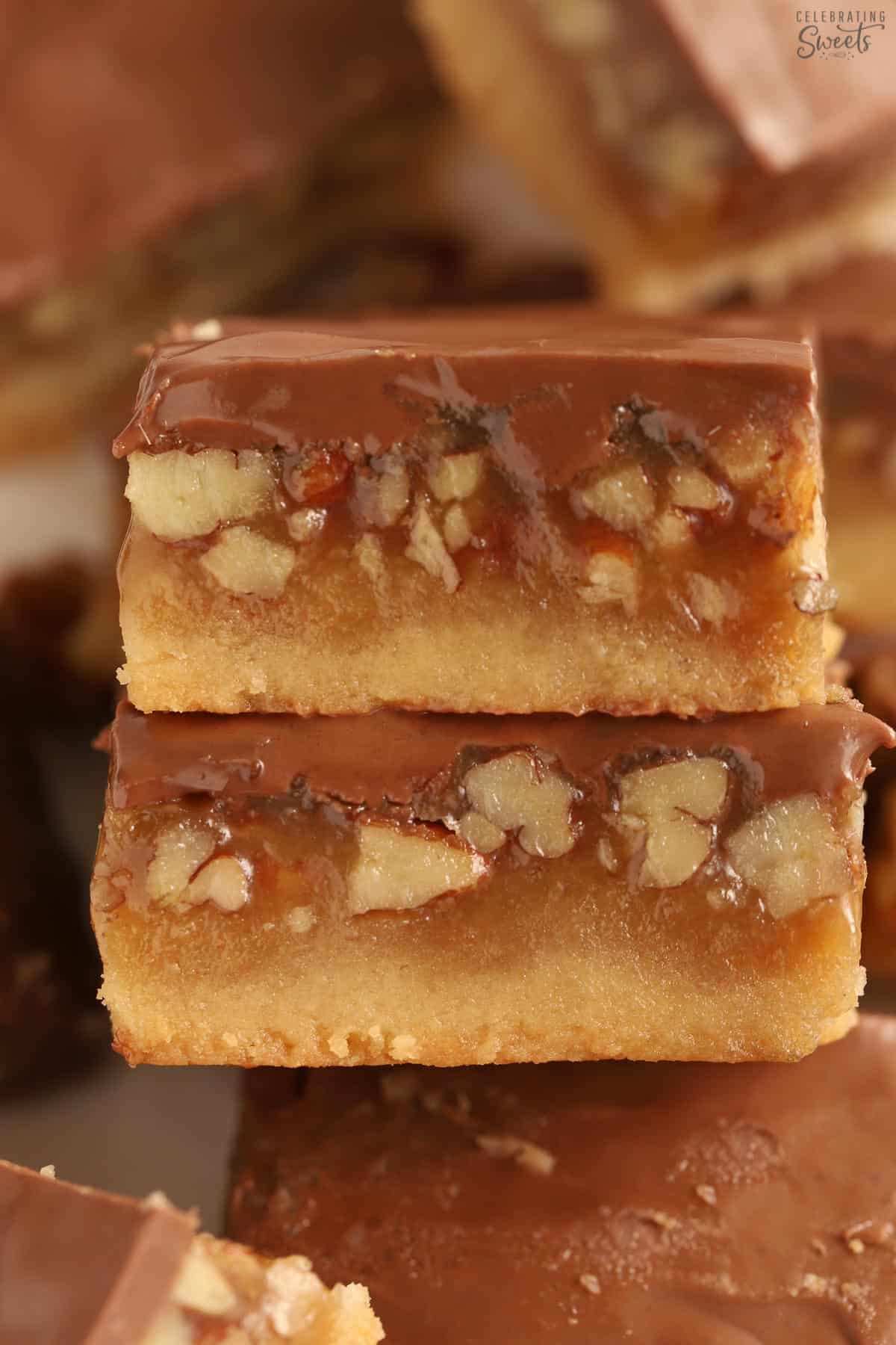 Closeup of two chocolate caramel pecan bars.