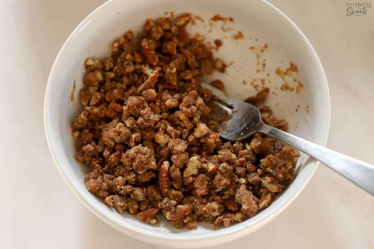 Pecan crumb topping in a white bowl with a fork in it.