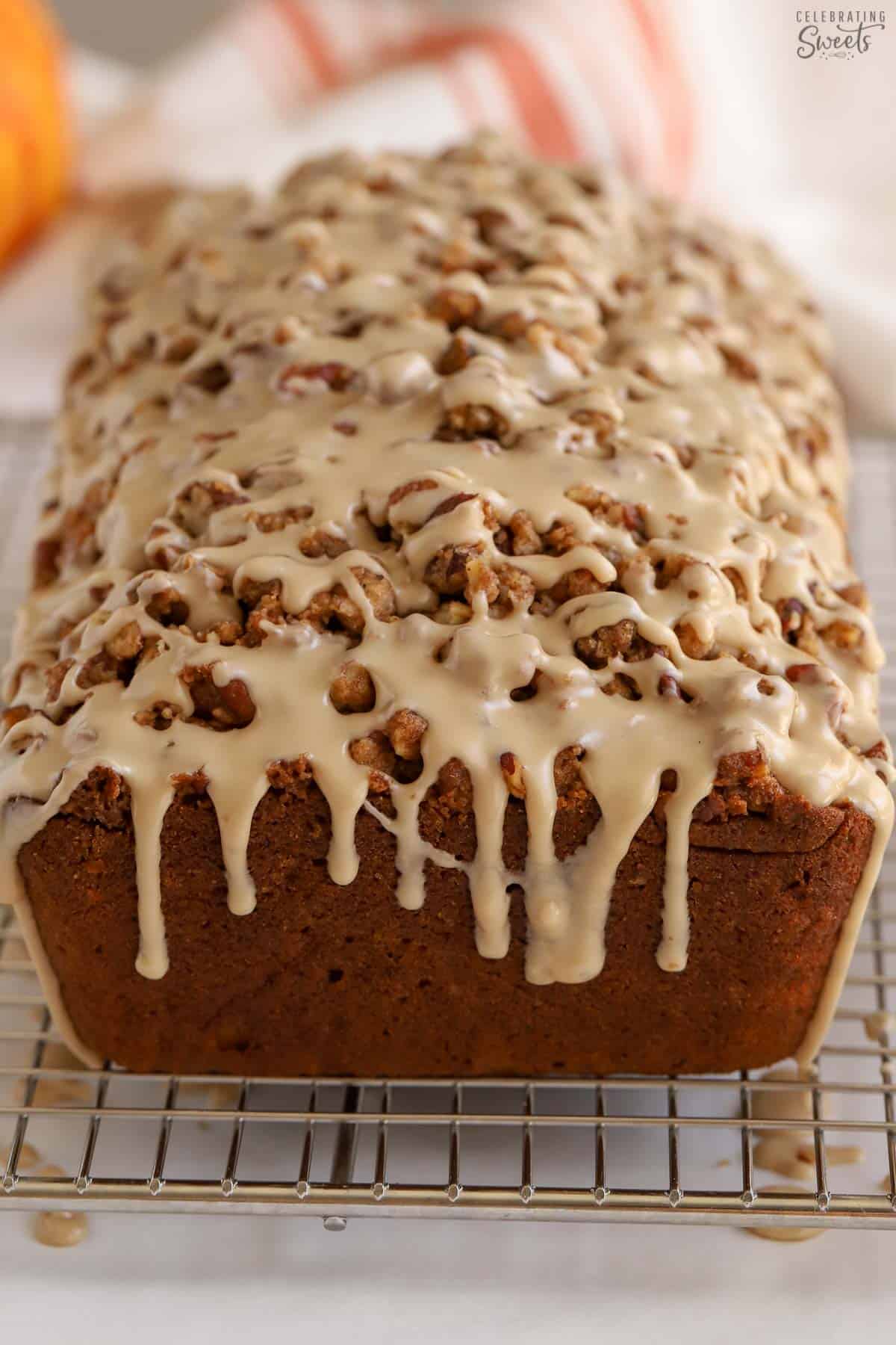 Loaf of pumpkin bread topped with icing on a wire rack.
