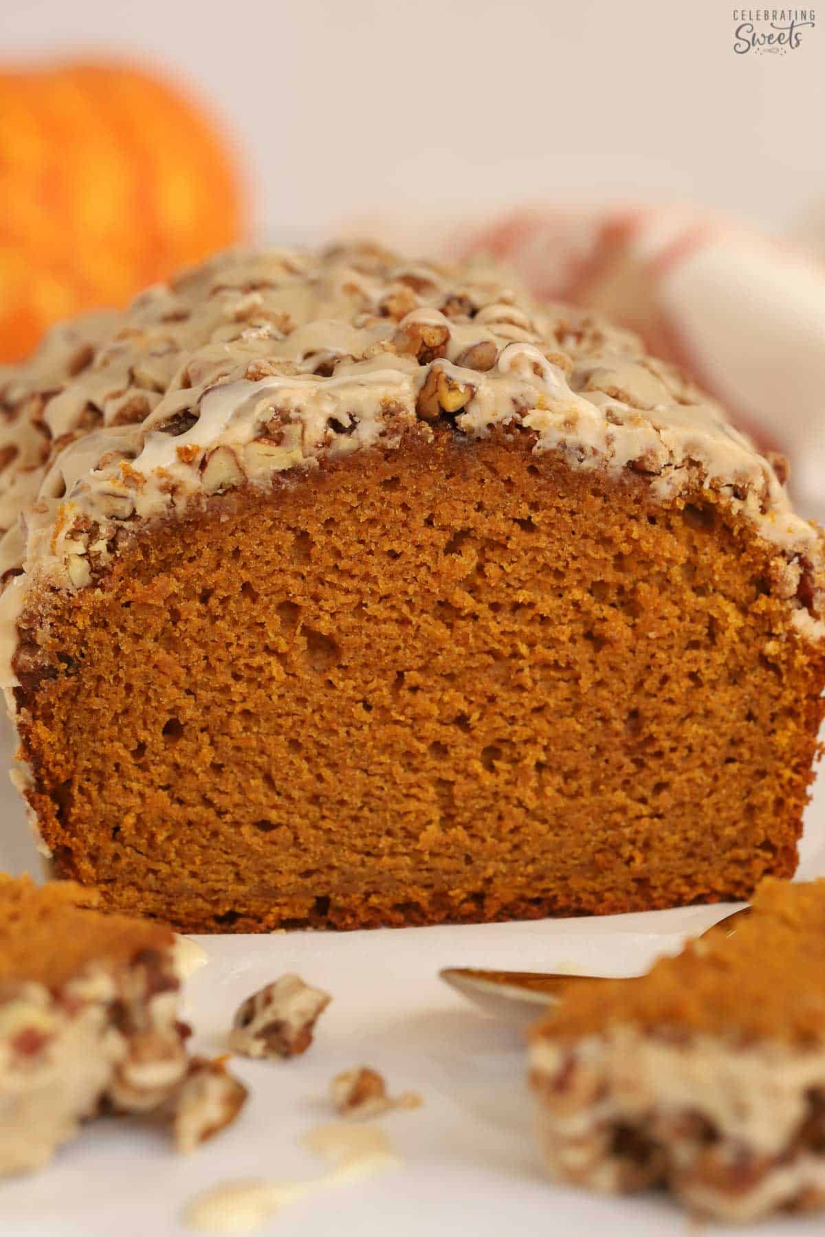 Loaf of pumpkin bread topped with nuts and icing.
