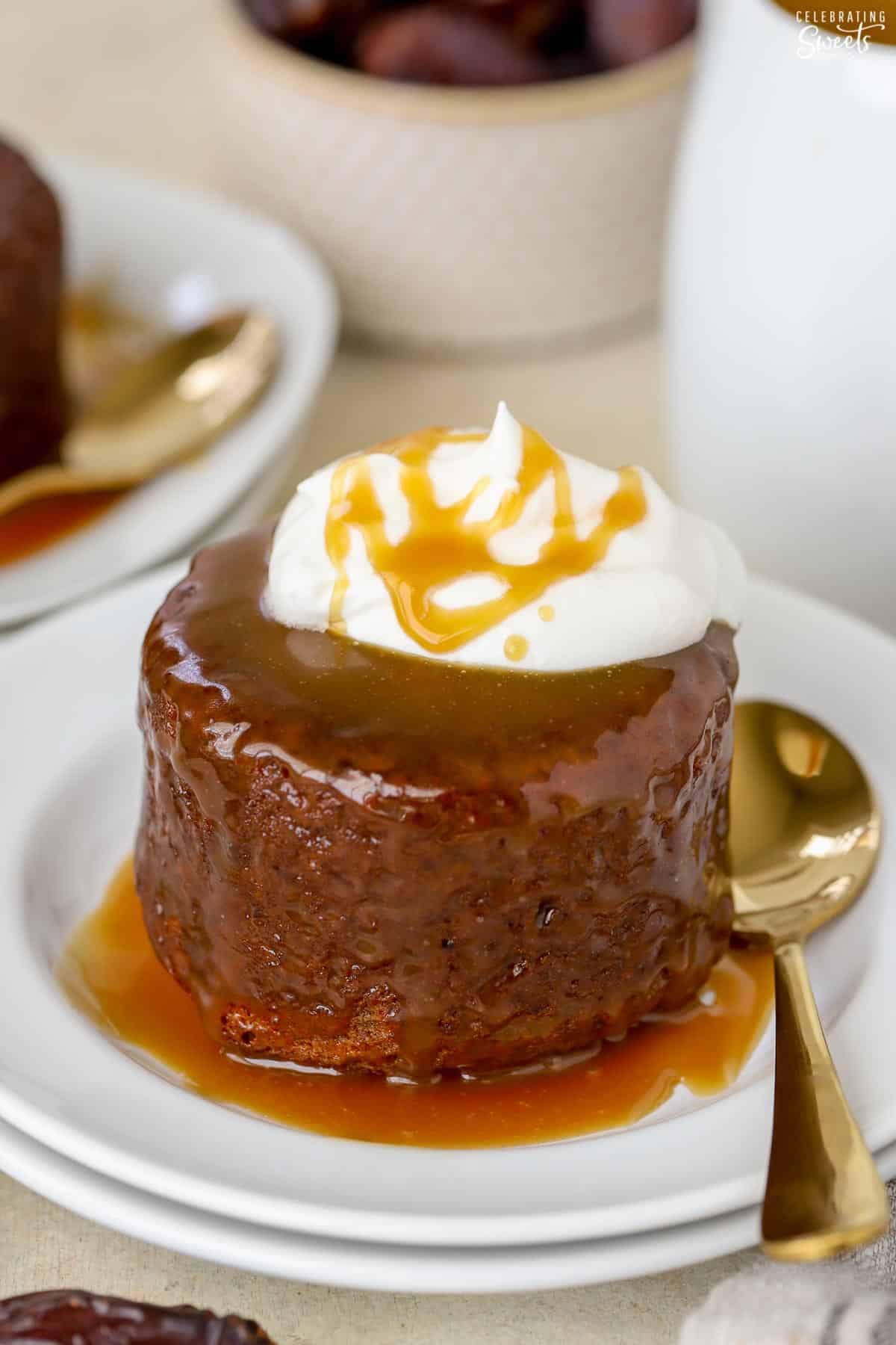 Sticky toffee pudding on a white plate with a gold fork.
