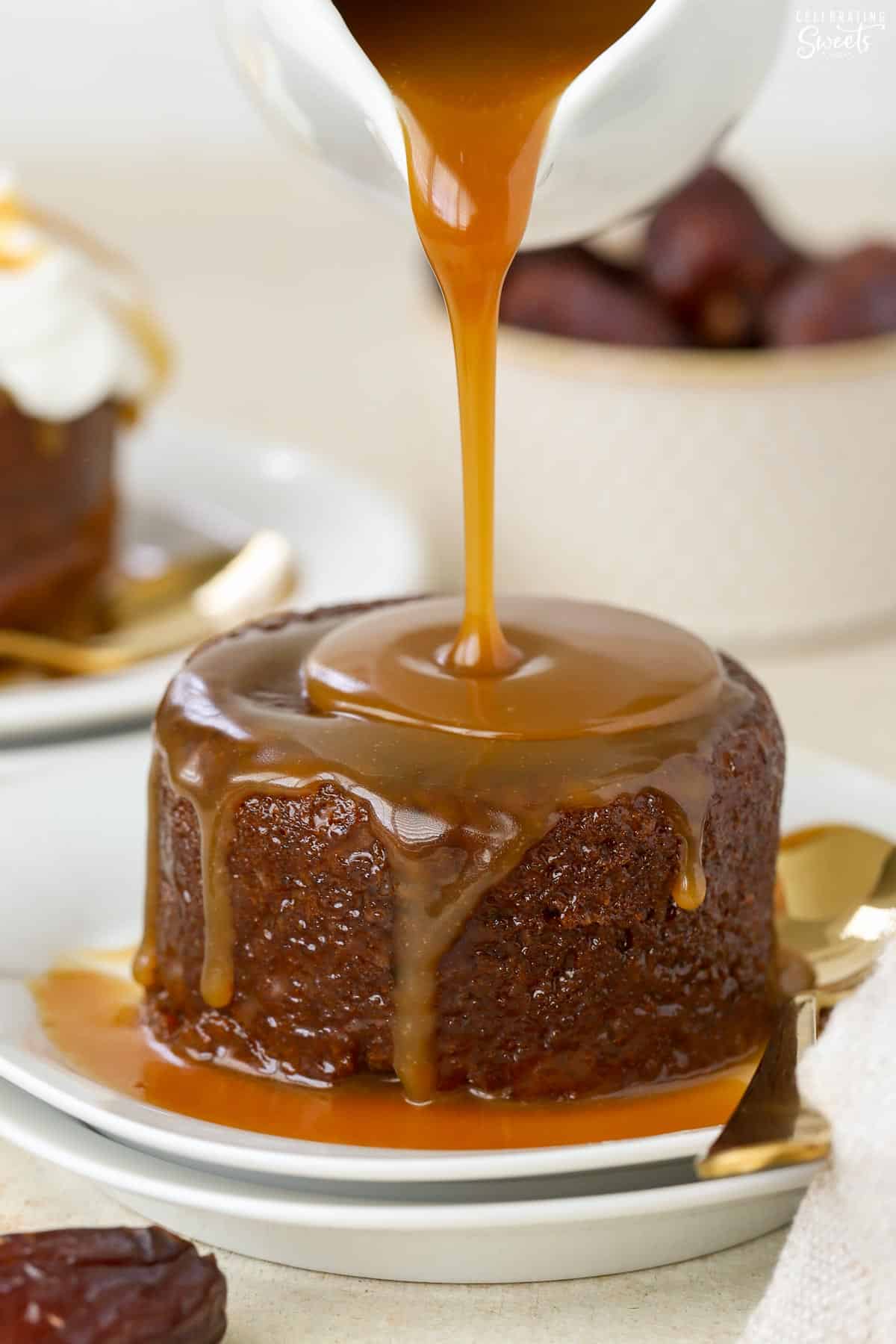 Toffee sauce being poured on sticky toffee pudding.