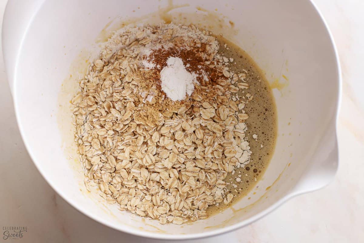 Oats, flour, spices, eggs, milk in a white bowl.