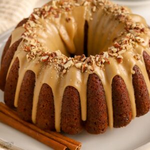 Bundt shaped spice cake covered in a maple glaze and topped with pecans.