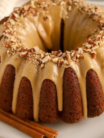 Bundt shaped spice cake covered in a maple glaze and topped with pecans.