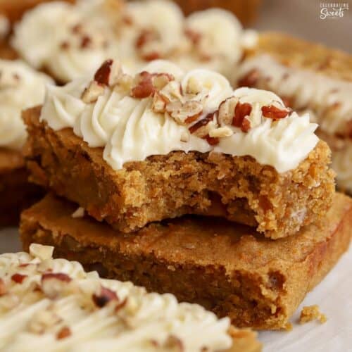 Two carrot cake bars stacked on top of each other with a bite taken out of it.
