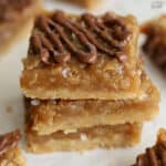 Stack of three caramel coconut bars on parchment paper.