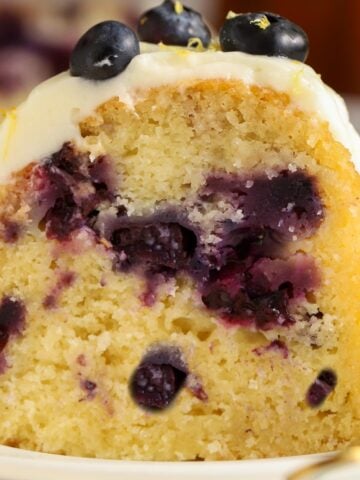 Closeup of a slice of lemon blueberry bundt cake on a white plate.