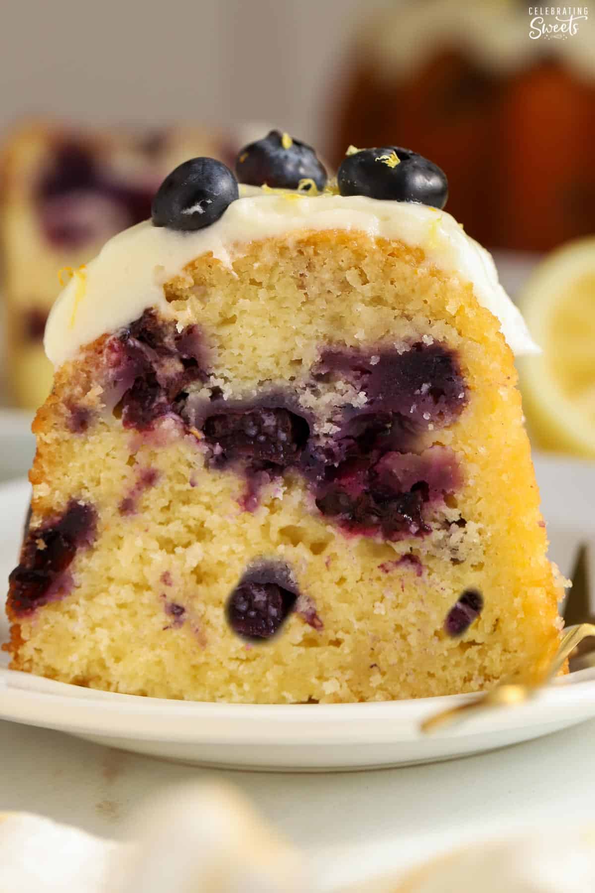 Closeup of a slice of lemon blueberry bundt cake on a white plate.