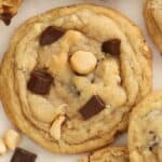 Closeup of a coconut chocolate chip cookie on parchment paper.
