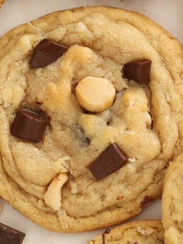 Closeup of a coconut chocolate chip cookie on parchment paper.