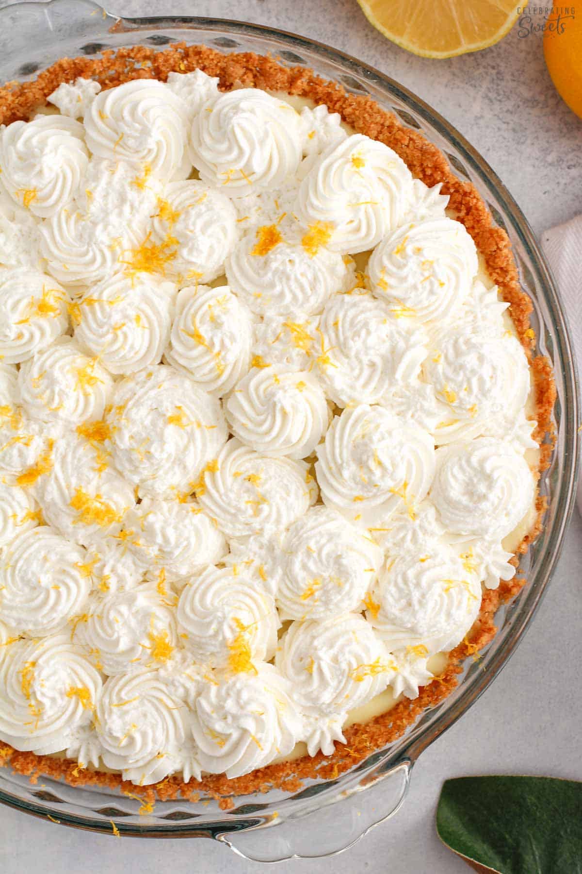 Overhead photo of lemon cream pie topped with whipped cream and lemon zest in a glass pie plate.