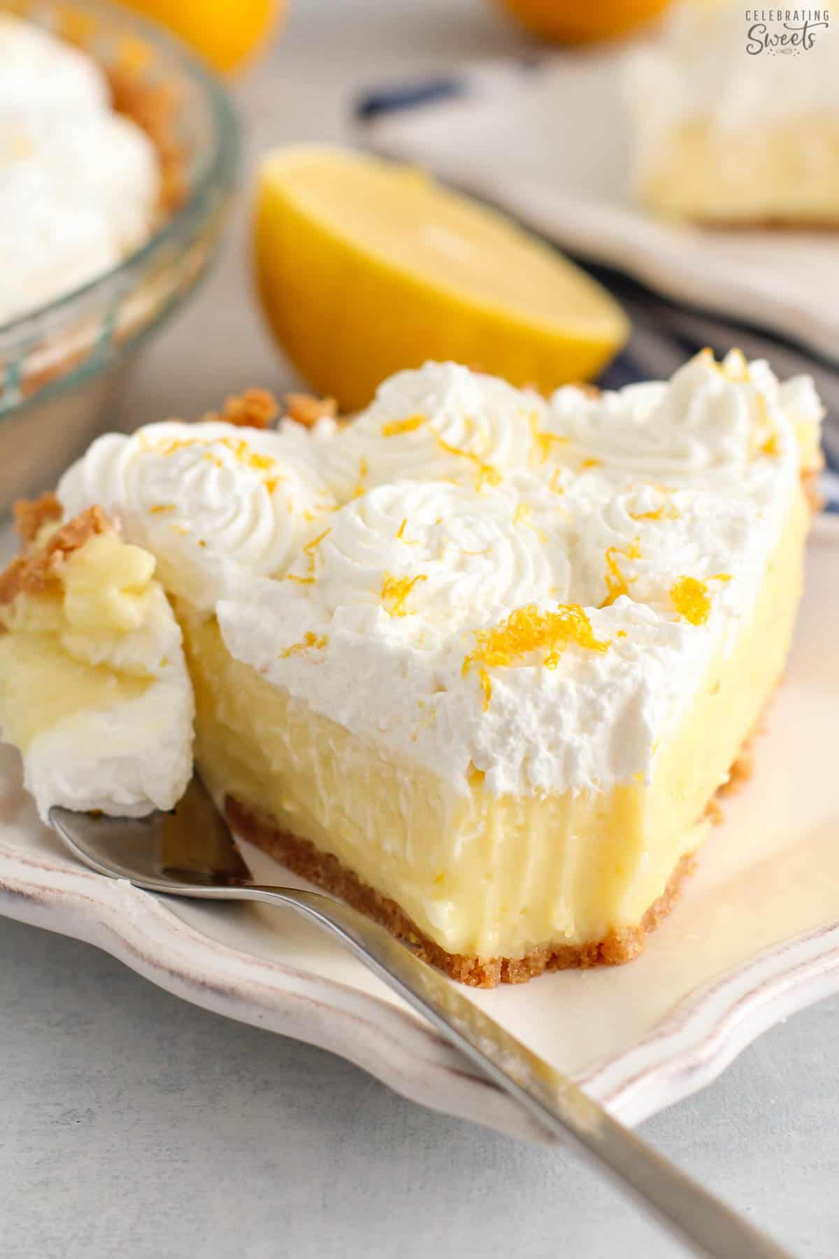 Slice of lemon cream pie on a white plate with a silver fork.