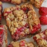 Raspberry bar on a piece of parchment paper with raspberries next to it.