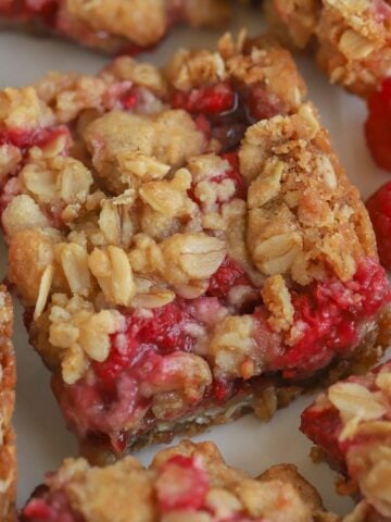 Raspberry bar on a piece of parchment paper with raspberries next to it.