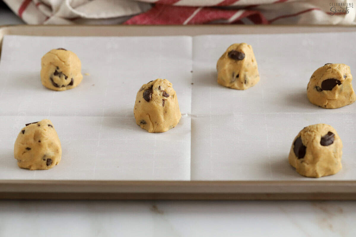 Cookie dough balls on a parchment lined baking sheet.