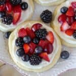 Sugar cookie fruit tarts topped with berries on a white plate.
