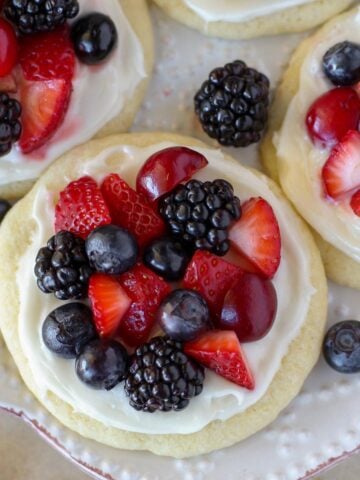 Sugar cookie fruit tarts topped with berries on a white plate.