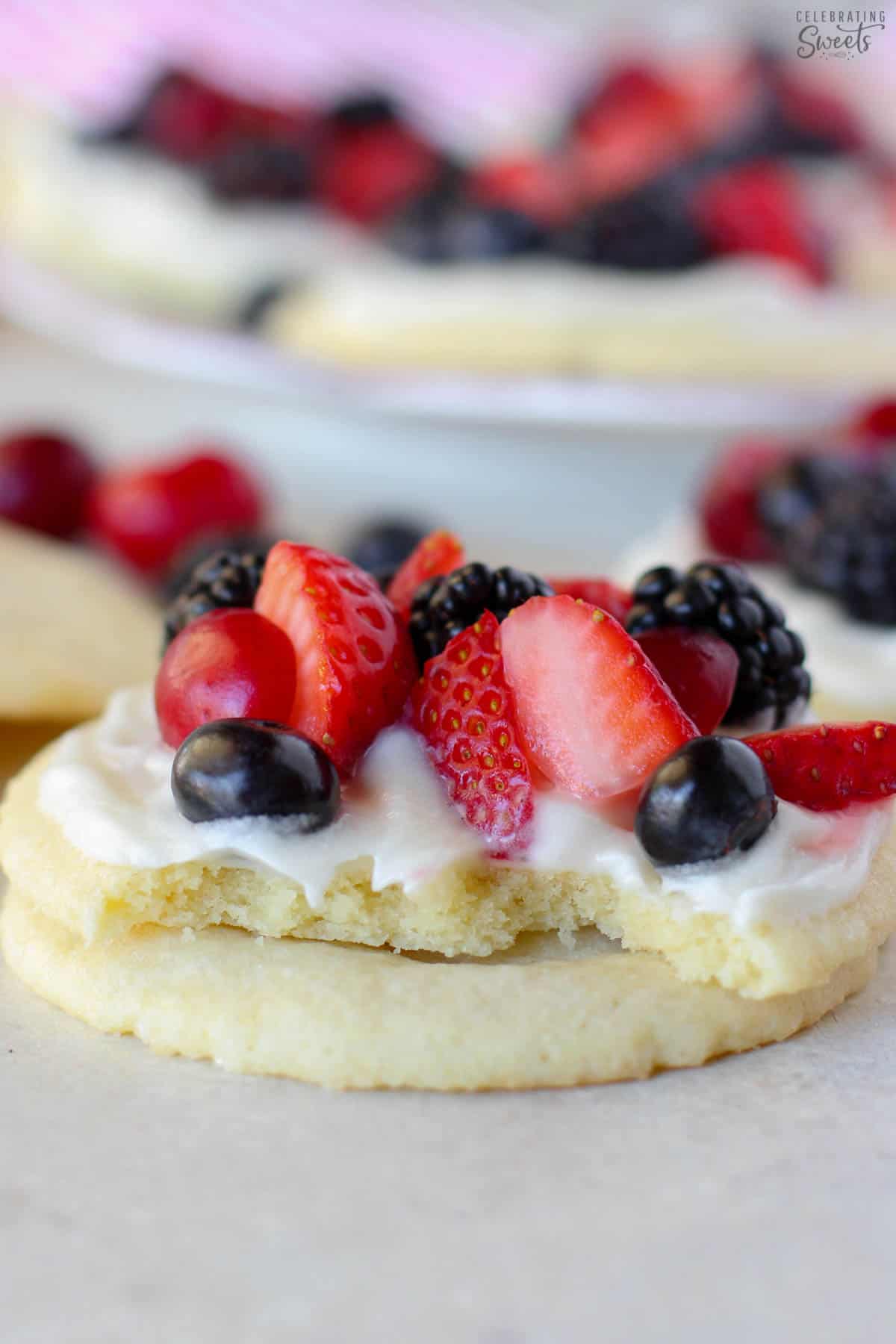 A stack of sugar cookie fruit tarts topped with berries.