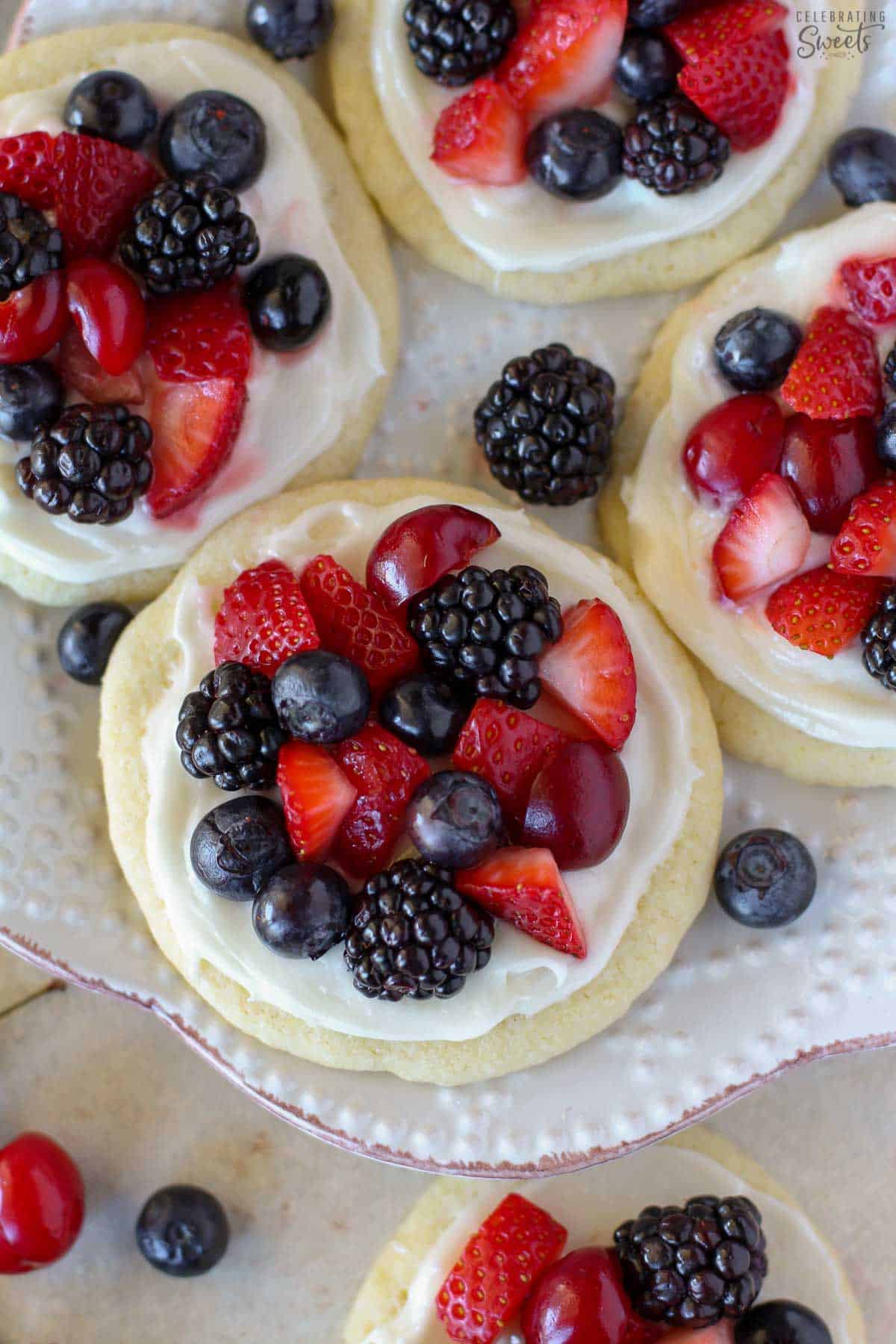 Sugar cookie fruit tarts topped with berries on a white plate.