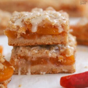 Stack of two peach crumb bars topped with white icing.