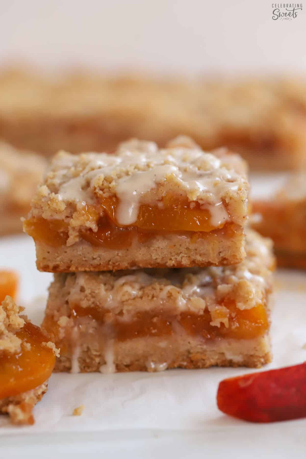Stack of two peach crumb bars topped with white icing.