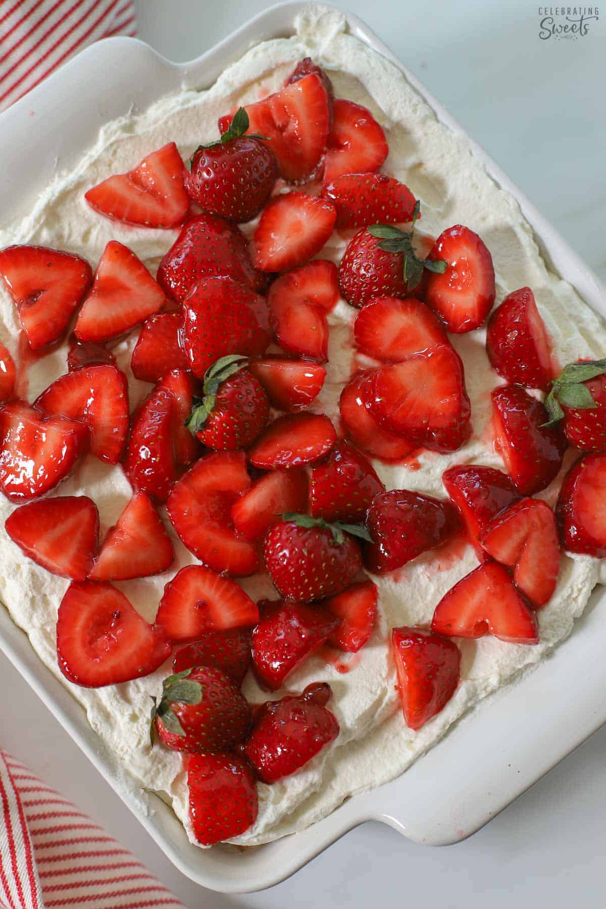 Strawberry icebox cake in a white baking dish next to a red and white striped napkin.