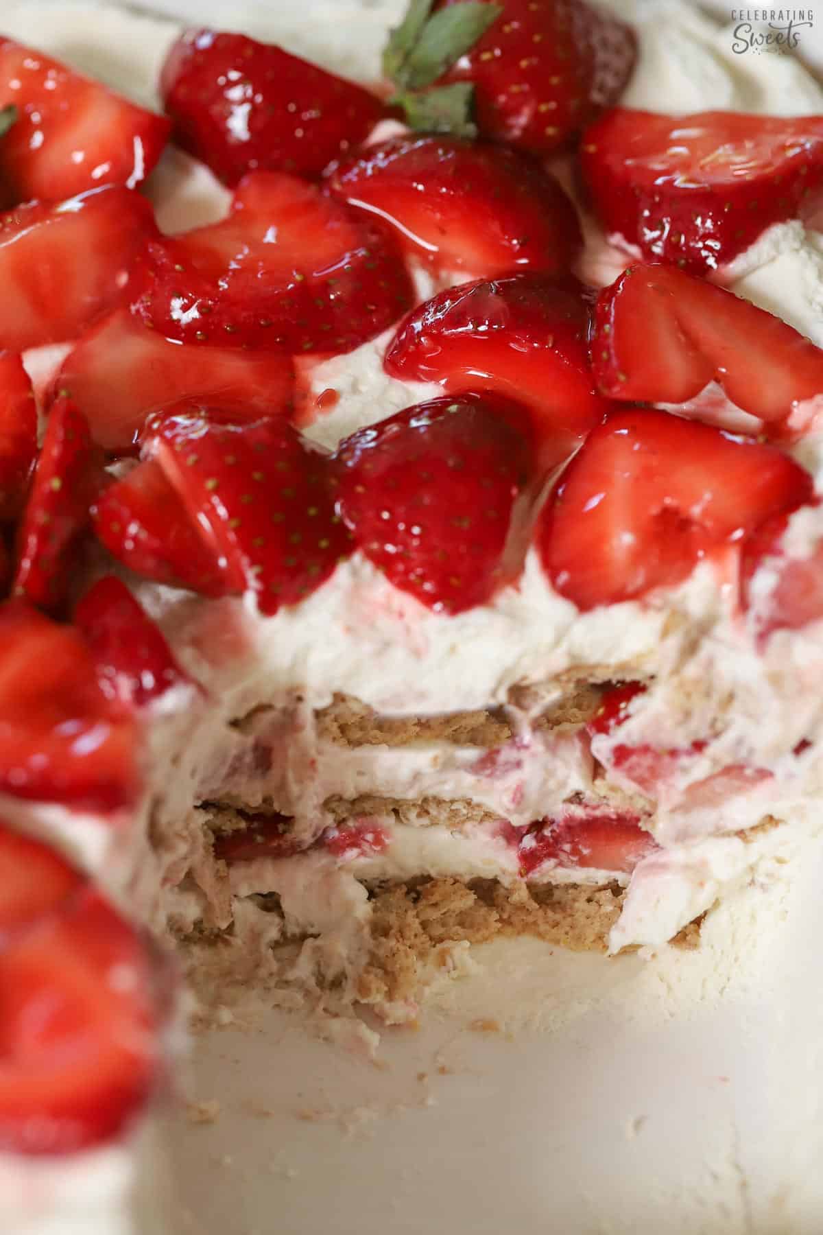 Strawberry icebox cake topped with fresh strawberries in a white baking dish.