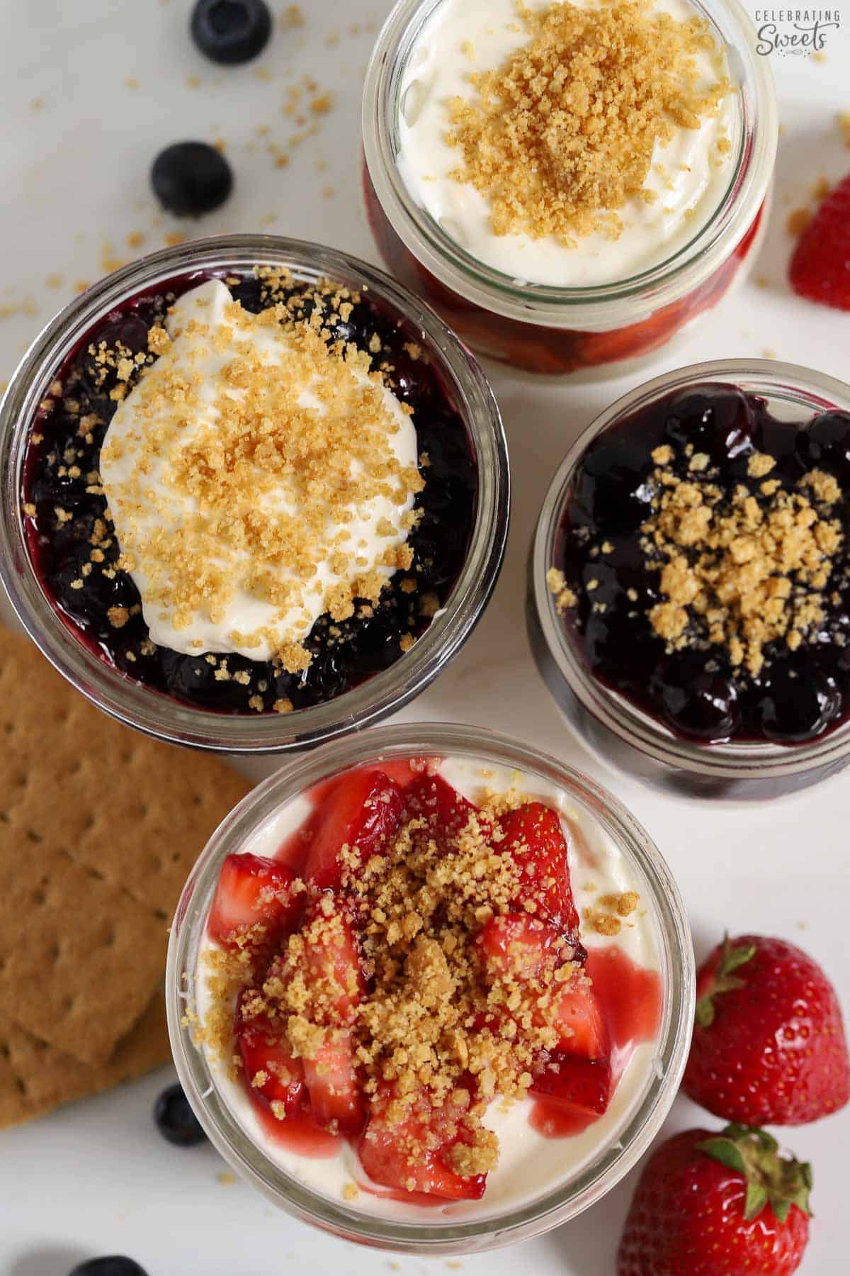 Overhead photo of four cheesecake parfaits in glass jars.