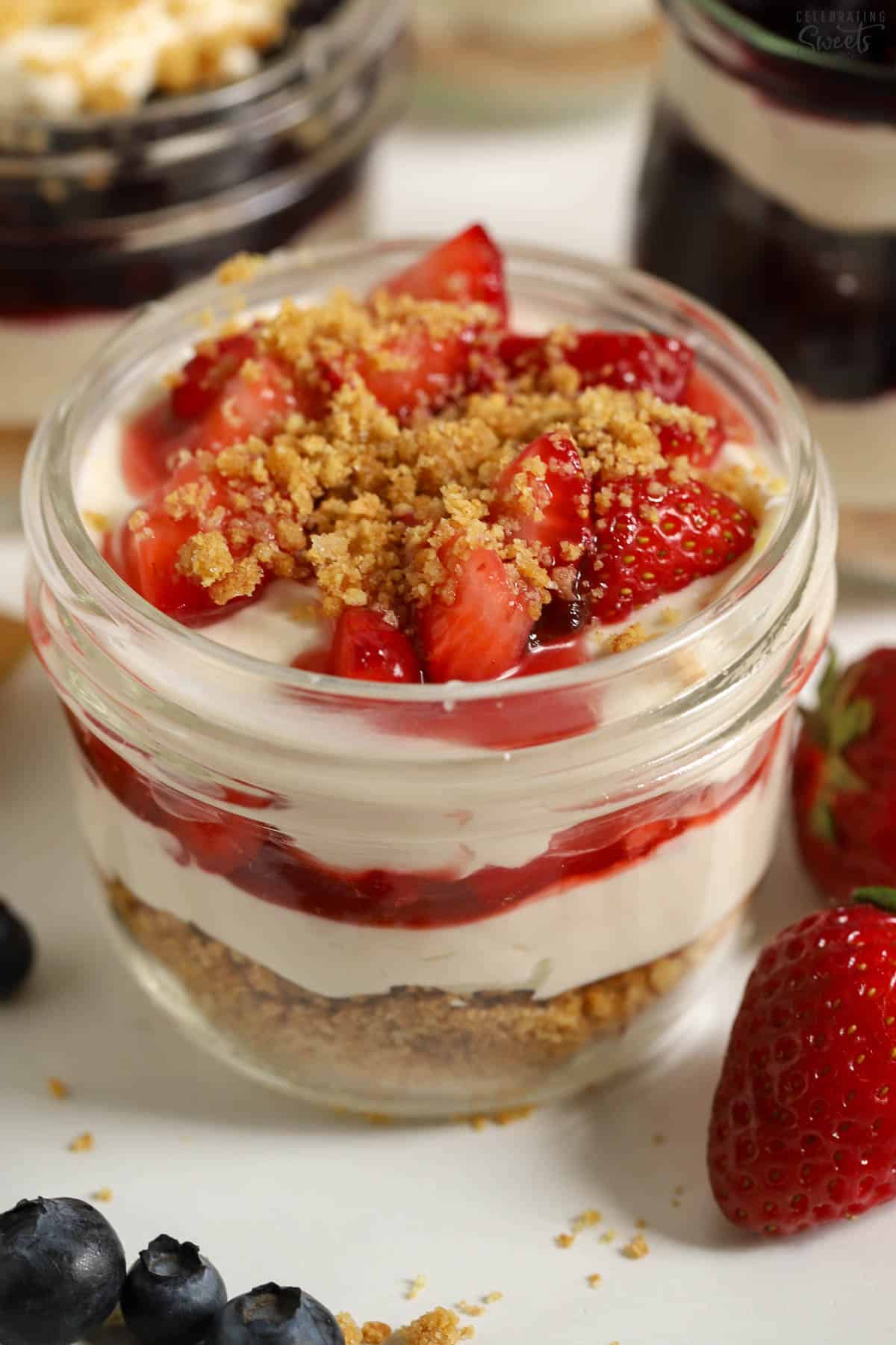 Cheesecake parfait with strawberry sauce in a glass jar.