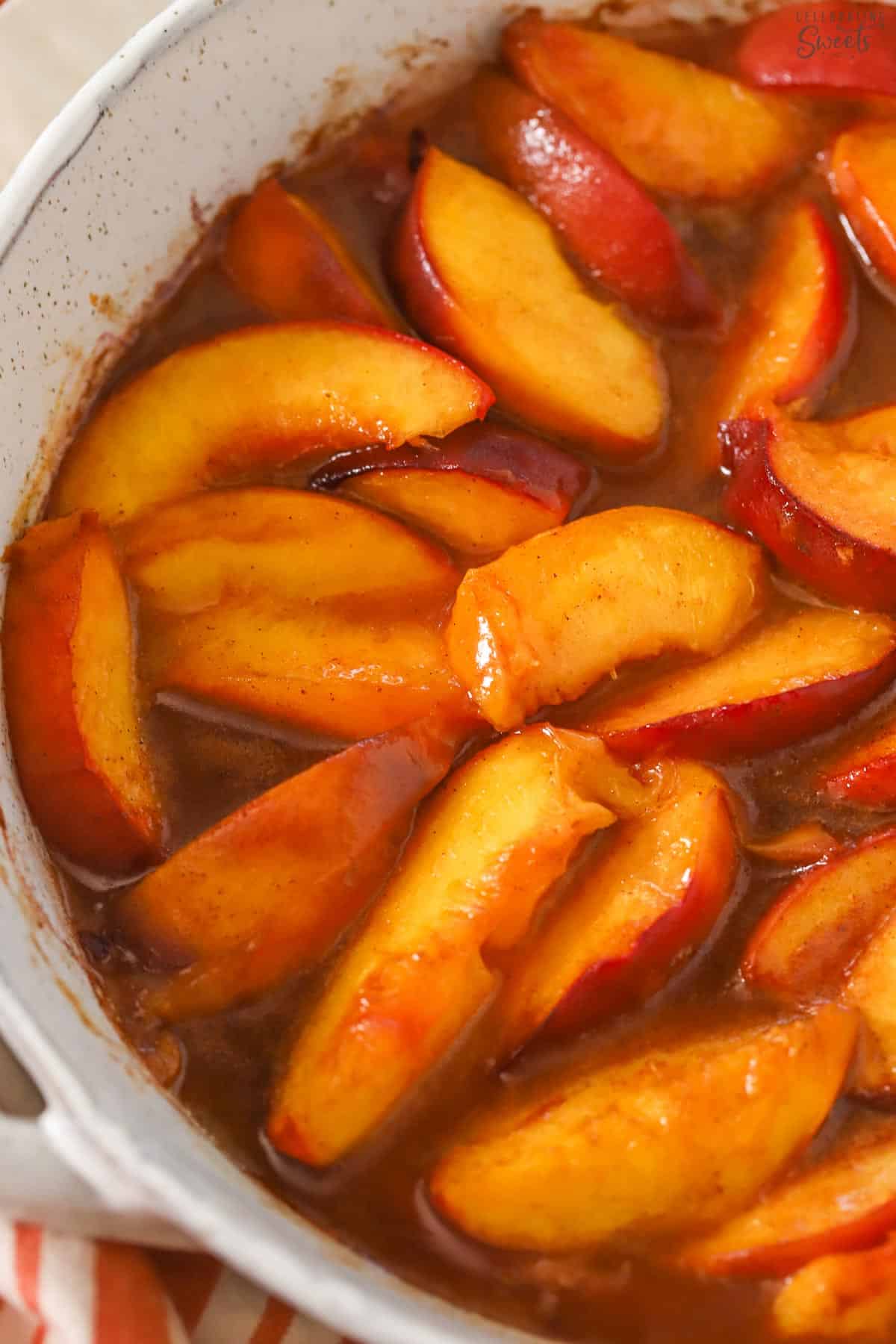 Sliced baked peaches in a grey baking dish.