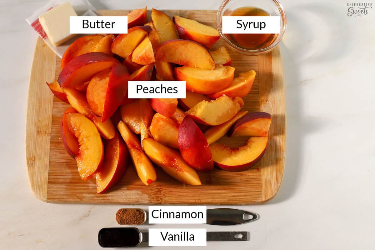 Ingredients for baked peaches on a wooden cutting board (sliced peaches, butter, syrup, cinnamon, and vanilla).