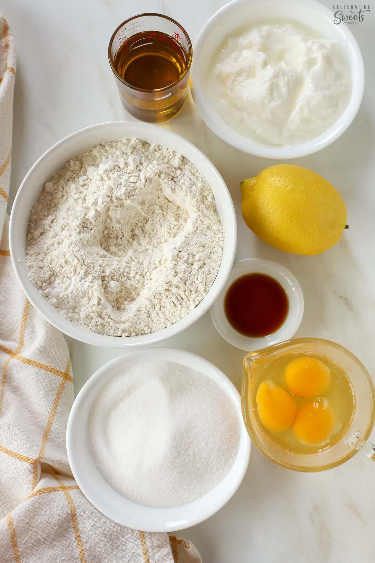 Ingredients to make a yogurt cake (flour, sugar, eggs, vanilla, lemon, oil, yogurt).