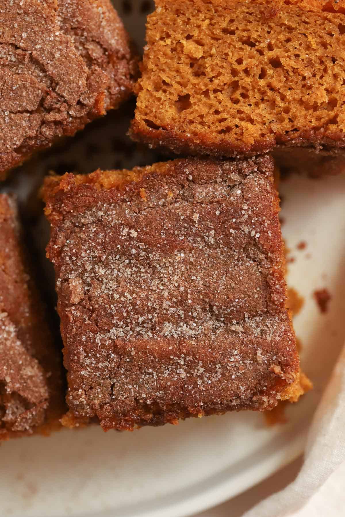 Closeup of a slice of pumpkin cake topped with cinnamon sugar on a plate.