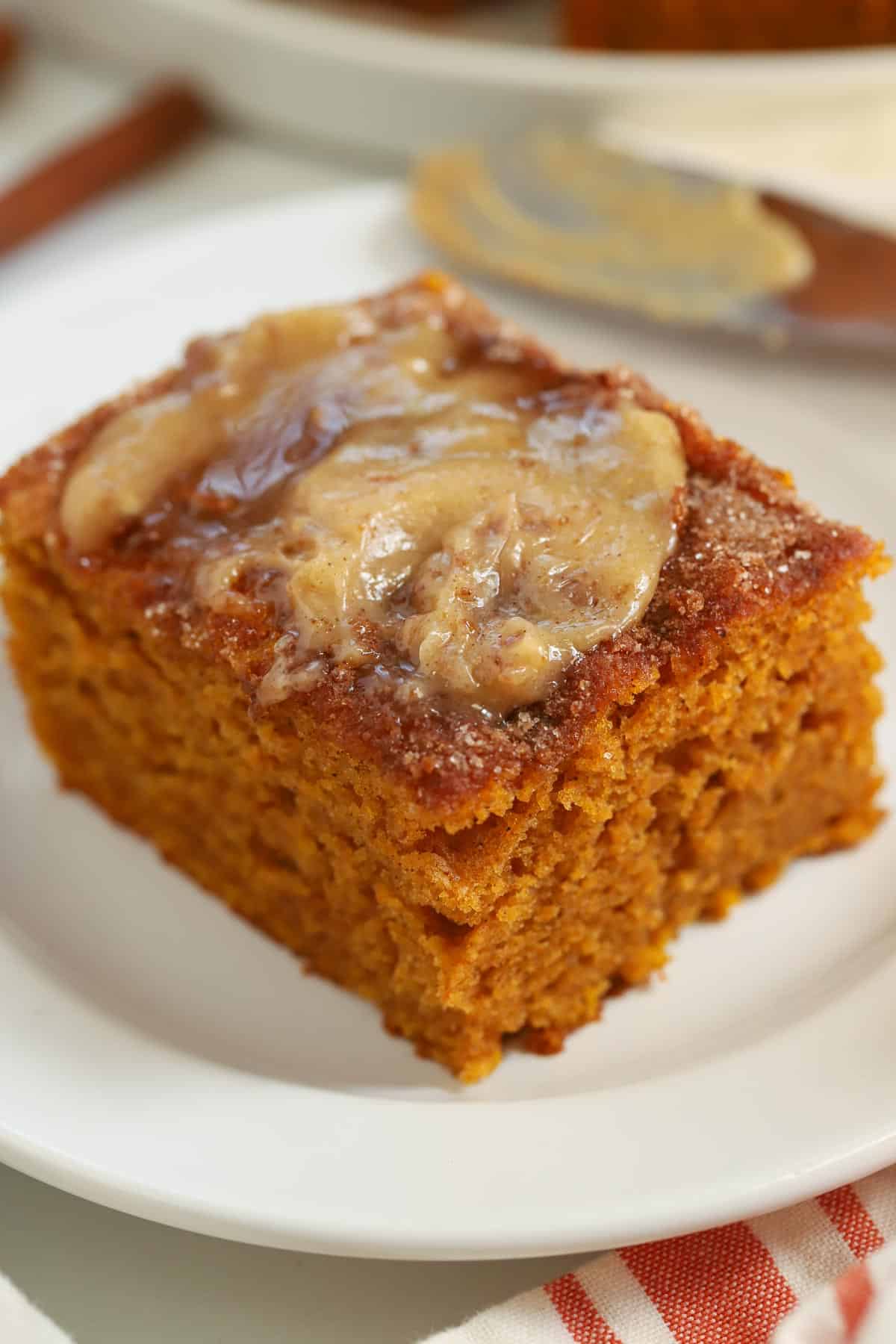 Slice of pumpkin cake topped with honey butter on a white plate.