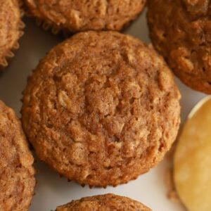 Overhead photo of an apple oatmeal muffin next to a spoon of applesauce.