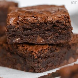 Stack of two brownies on top of each other with a knife next to them.