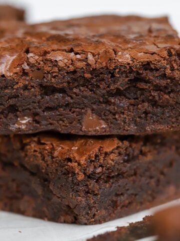 Stack of two brownies on top of each other with a knife next to them.