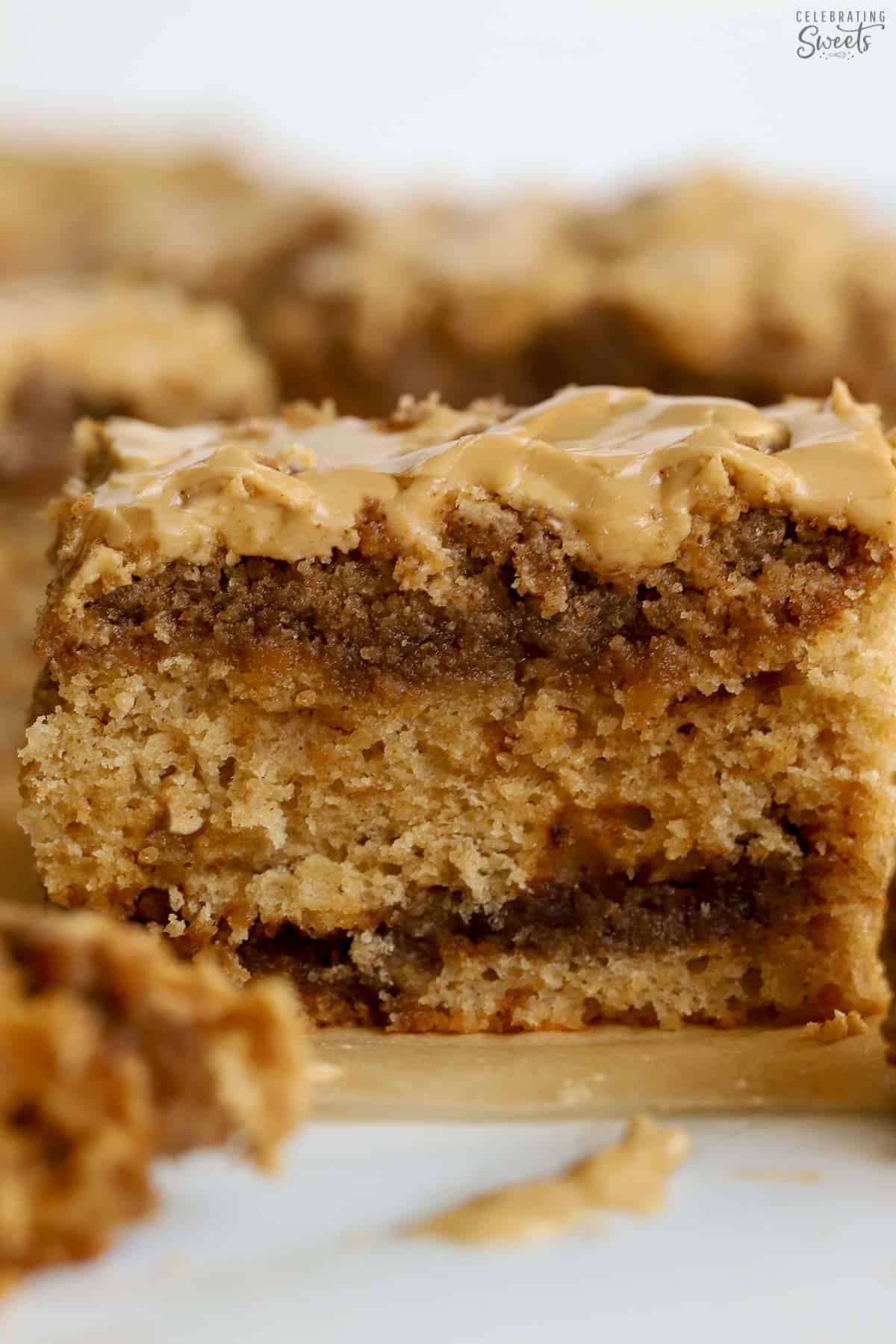 Thick slice of crumb cake topped with beige icing and a brown sugar swirl.