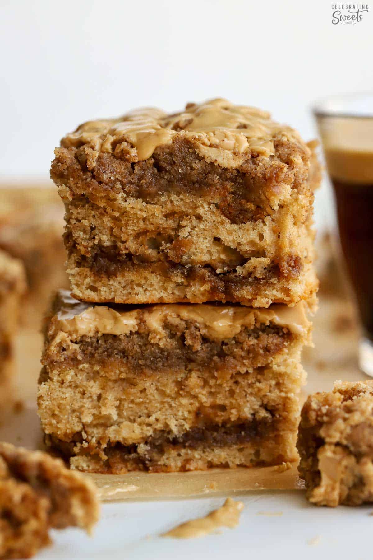 Two slices of crumb cake stacked on top of each other with a glass of coffee in the background.